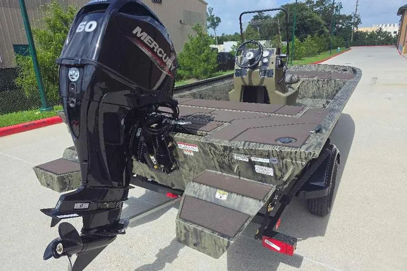 Slide: The Image of 2026 Tracker Grizzly 1860 CC boat with Mercury engine, parked outdoors on a sunny day. - 3