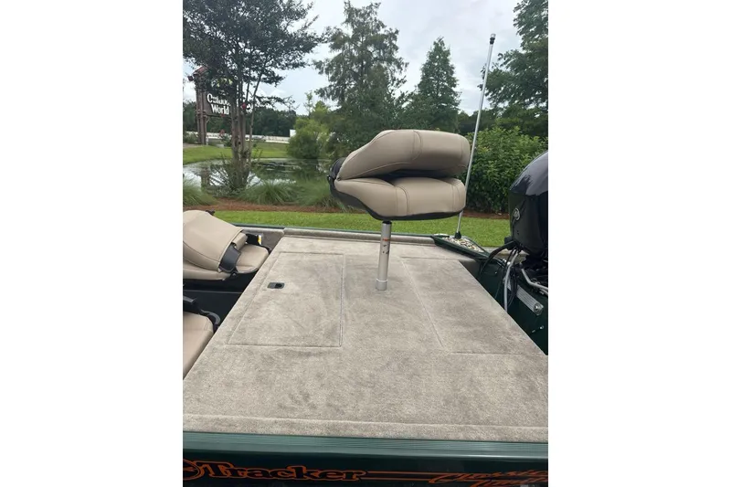 Slide: The Image of 2026 Tracker Bass Tracker Classic Limited boat with cushioned seating, outdoors near greenery. - 6