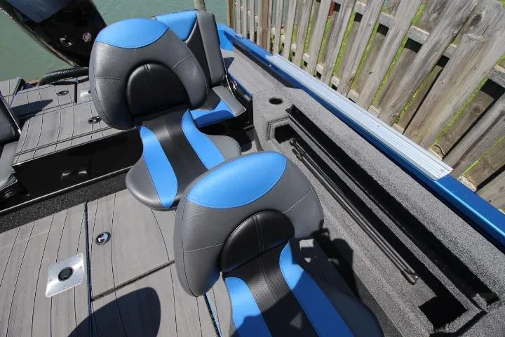 Slide: The Image of 2026 Vexus ADX 190 boat interior with blue and black seating, docked by wooden fence. - 10