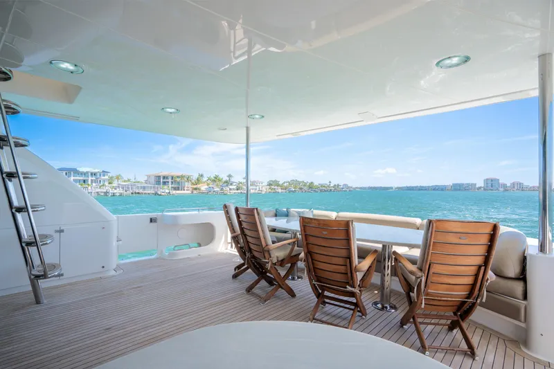 Slide: The Image of Luxurious 2001 Lazzara 94 yacht deck with wooden chairs overlooking serene waterfront views. - 6