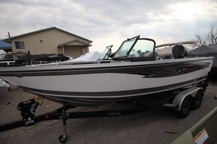 The Image of 2026 Lund 2075 Tyee boat on trailer, parked outdoors under cloudy sky. - 0