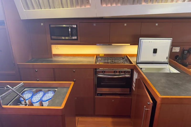 Slide: The Image of Modern kitchen in a 2015 Beneteau Oceanis 48 yacht with stove, microwave, and sink. - 2