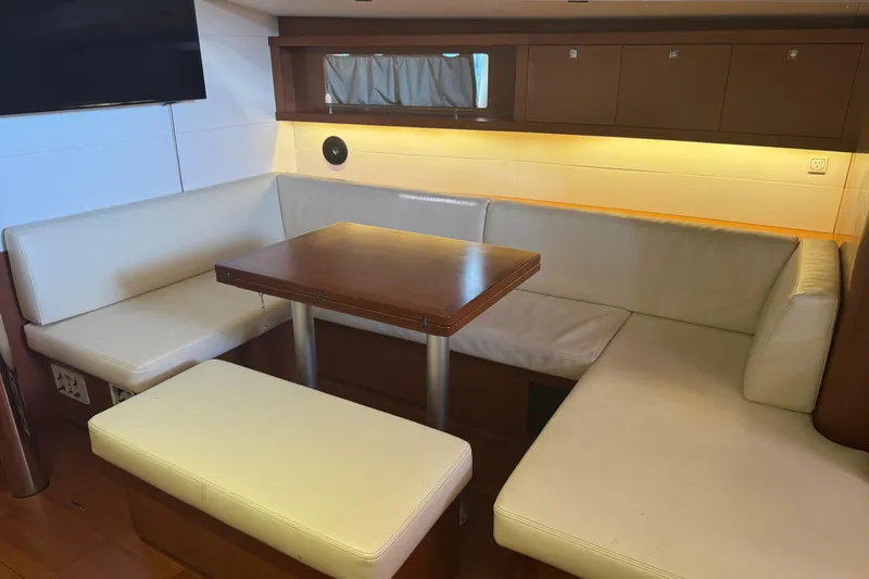 Slide: The Image of Interior of 2015 Beneteau Oceanis 48 yacht with cozy seating and wooden table. - 3