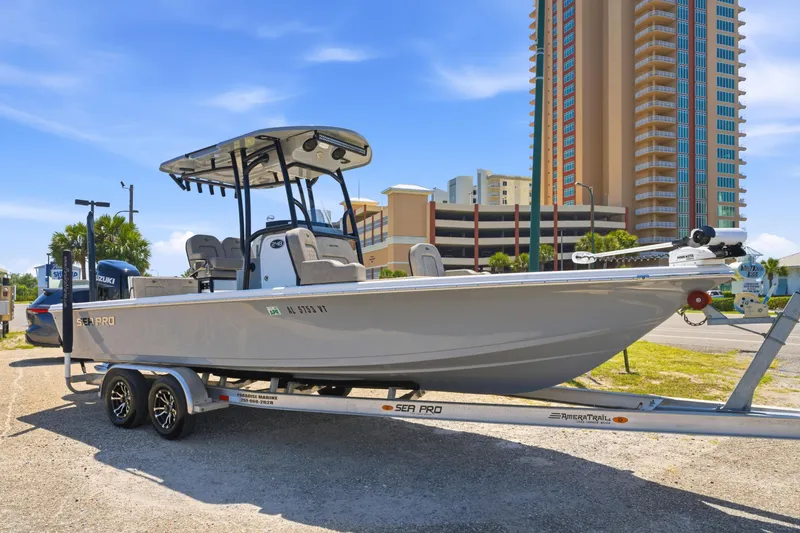 The Image of 2023 Sea Pro 248 Bay boat on trailer, parked near tall buildings under clear blue sky. - 0