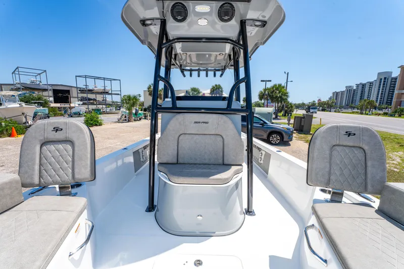 Slide: The Image of 2023 Sea Pro 248 Bay boat interior with seating and console, parked outdoors. - 16
