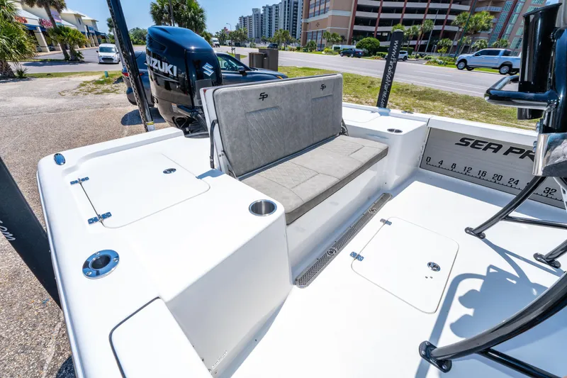 Slide: The Image of 2023 Sea Pro 248 Bay boat interior with seating and Suzuki engine, parked outdoors. - 18