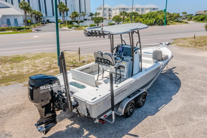 Slide: The Image of 2023 Sea Pro 248 Bay boat with Suzuki engine on a trailer, parked near a road. - 2