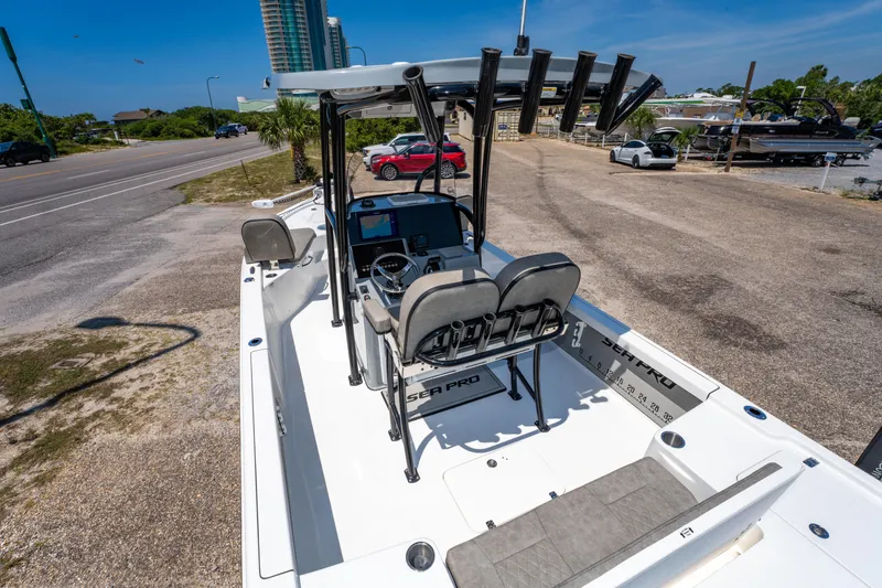 Slide: The Image of 2023 Sea Pro 248 Bay boat with dual seats and modern dashboard, parked near a road. - 24