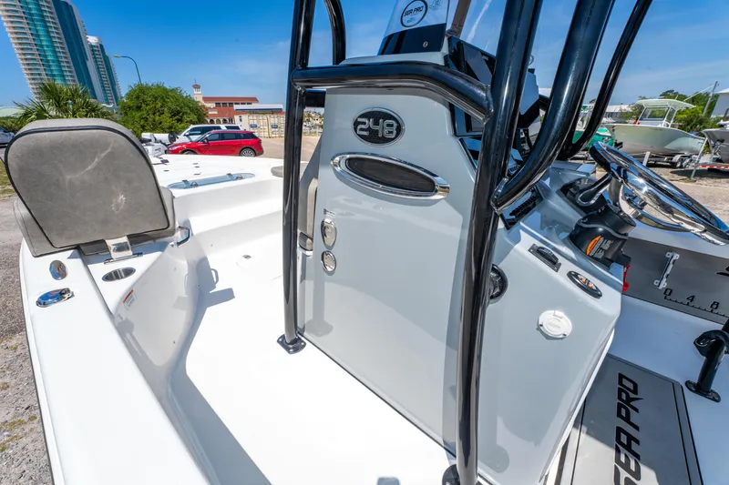 Slide: The Image of 2023 Sea Pro 248 Bay boat interior with steering console and seating, parked outdoors. - 29