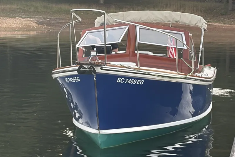 Slide: The Image of 1973 Dyer 29 Bass Boat with blue hull, docked on calm water. - 5