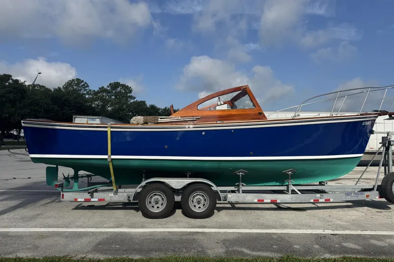 Slide: The Image of 1973 Dyer 29 Bass Boat on trailer, blue hull, parked outdoors under cloudy sky. - 9