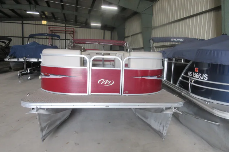 Slide: The Image of 2014 Manitou 22 Aurora pontoon boat in storage, featuring red and white design. - 1