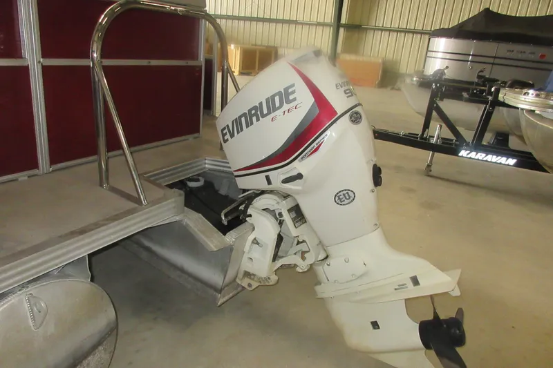 Slide: The Image of 2014 Manitou 22 Aurora with Evinrude E-TEC outboard motor in a storage facility. - 7