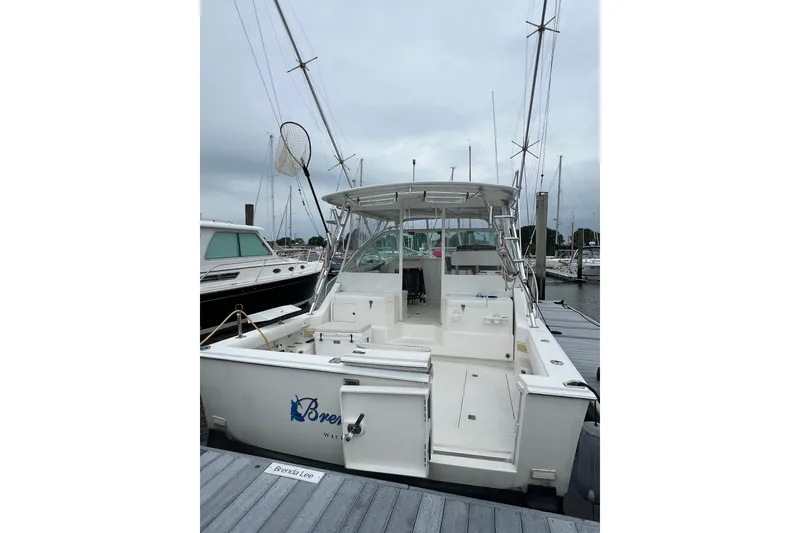 Slide: The Image of 1999 Cabo 35 Express boat docked at marina, featuring spacious deck and fishing equipment. - 1