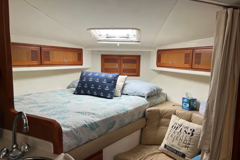 Slide: The Image of Cozy cabin interior of 1999 Cabo 35 Express boat with bed and wooden storage cabinets. - 14