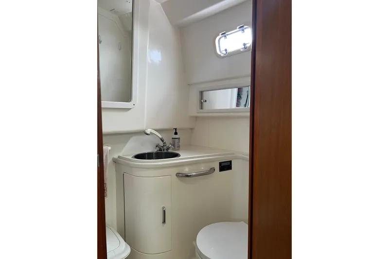 Slide: The Image of 1999 Cabo 35 Express yacht bathroom with sink, mirror, and porthole window. - 17