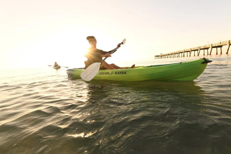 The Image of Person kayaking on Ocean Kayak Malibu 11.5, 2023 model, at sunset near a pier. - 0