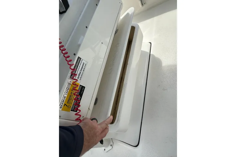 Slide: The Image of 2025 Key West 219 FS boat storage compartment with safety labels and red coiled cord. - 35