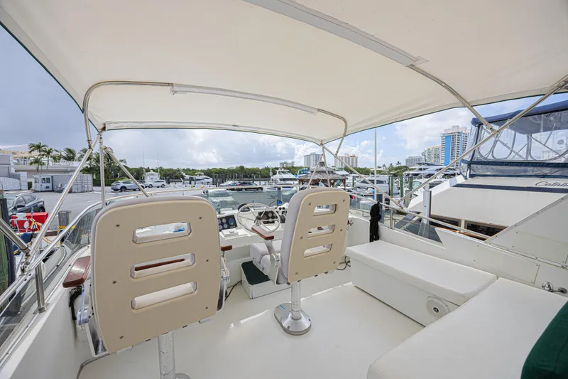 Slide: The Image of 1994 Tollycraft 45 Cockpit Motor Yacht helm with marina view, featuring dual seats and canopy. - 14