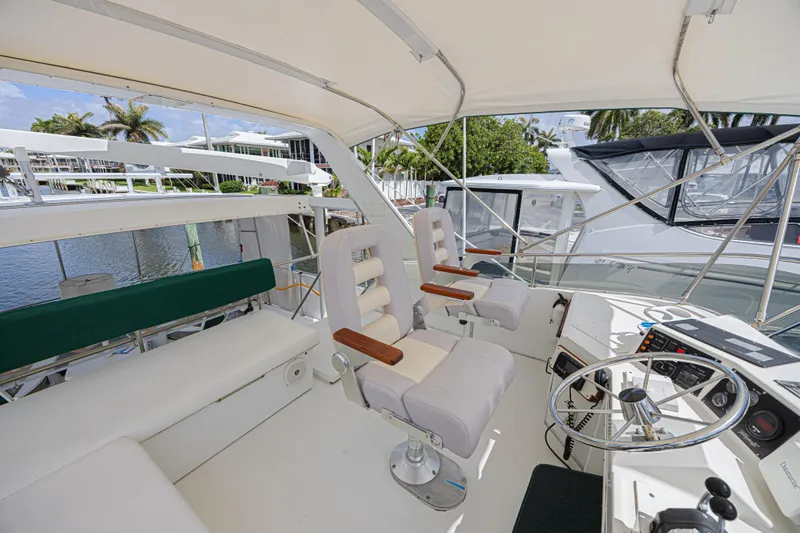 Slide: The Image of 1994 Tollycraft 45 Cockpit Motor Yacht helm with seating and steering wheel, docked by water. - 15