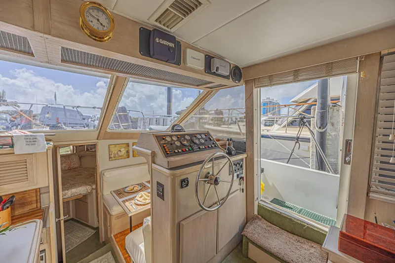 Slide: The Image of 1994 Tollycraft 45 Cockpit Motor Yacht interior with helm, dining area, and marina view. - 29