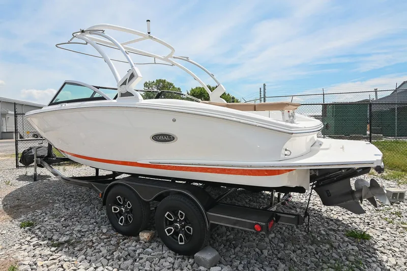 Slide: The Image of 2022 Cobalt CS22 boat on trailer, white exterior, parked on gravel lot. - 2