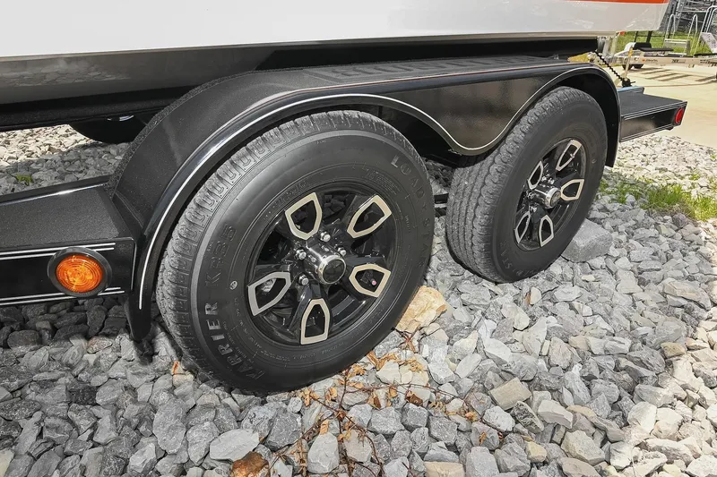Slide: The Image of Trailer wheels of a 2022 Cobalt CS22 boat on rocky ground. - 53