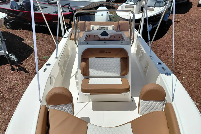 Slide: The Image of 2026 Pioneer 180 Islander boat interior with tan and white seating, docked outdoors. - 10