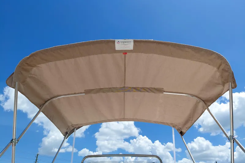 Slide: The Image of 2026 Pioneer 180 Islander boat canopy against a bright blue sky with clouds. - 33
