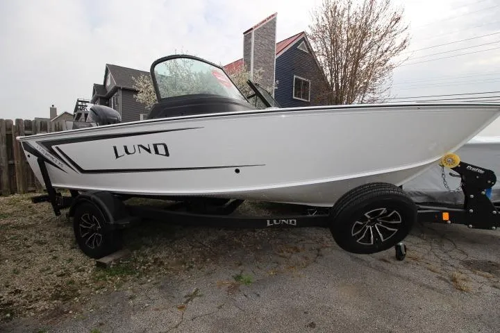The Image of 2025 Lund 1775 Impact XS Sport boat on trailer, parked outdoors. - 0