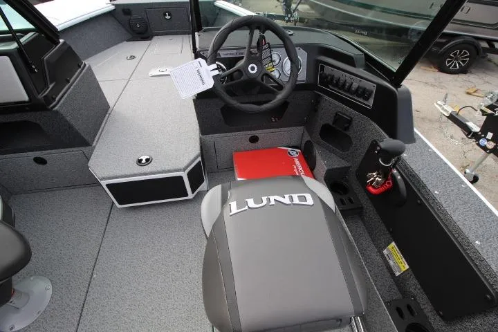 Slide: The Image of 2025 Lund 1775 Impact XS Sport boat interior with steering wheel and branded seat. - 9