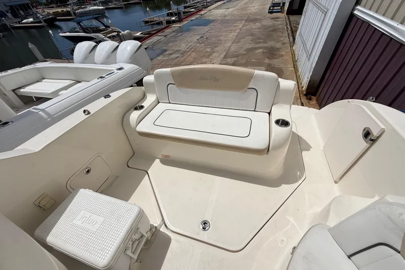 Slide: The Image of 2010 Sea Ray 240 Sundancer boat interior with seating and cooler, docked at marina. - 19