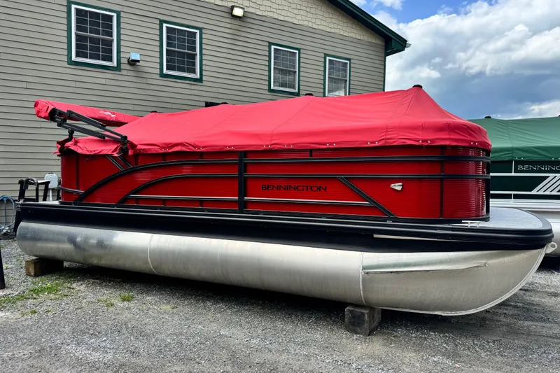 The Image of 2026 Bennington S 20 SSR pontoon boat with red cover, parked outdoors. - 1