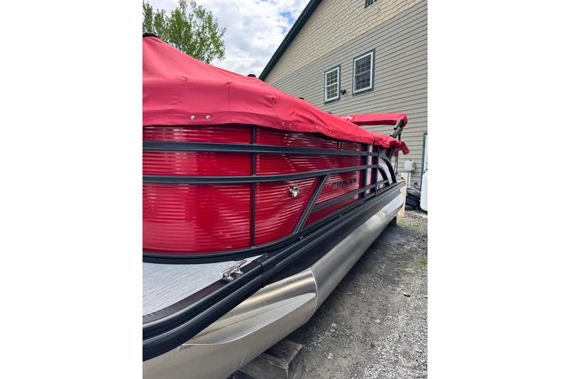 Slide: The Image of 2026 Bennington S 20 SSR pontoon boat with red cover, parked outdoors. - 3