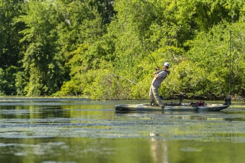 Slide: The Image of Person fishing on a 2023 Hobie Outback kayak in a lush, green lake. - 4