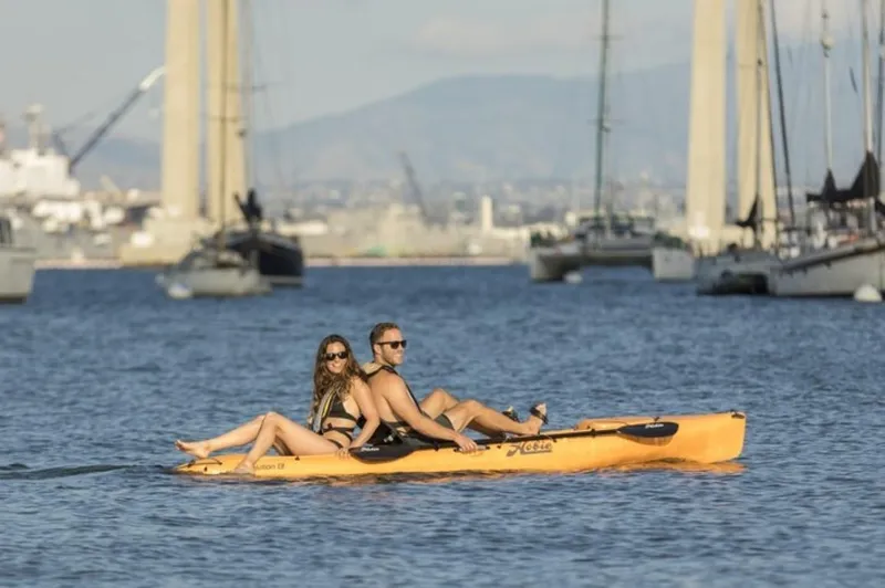 Slide: The Image of Couple kayaking on a 2023 Hobie Revolution 13 in a scenic harbor. - 2