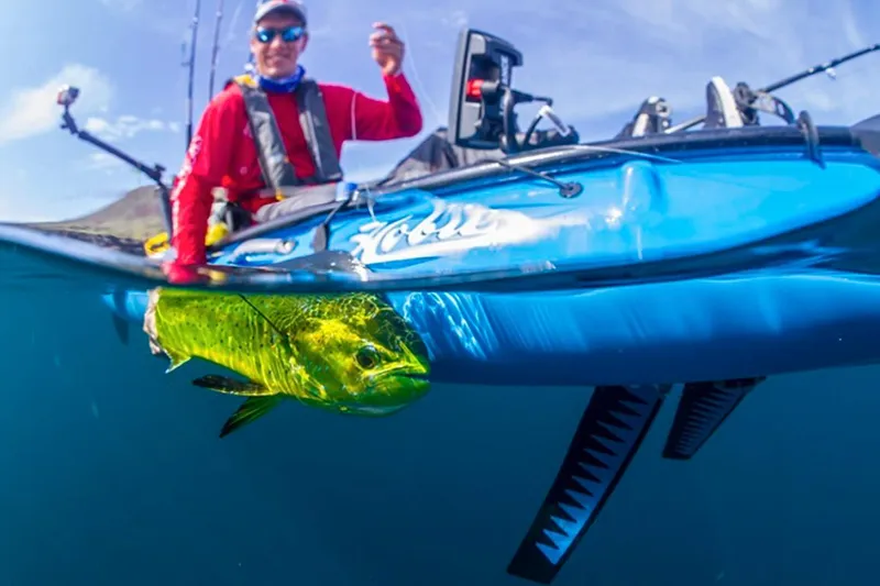 Slide: The Image of Angler on 2023 Hobie Revolution 13 kayak with a caught fish in clear blue water. - 6