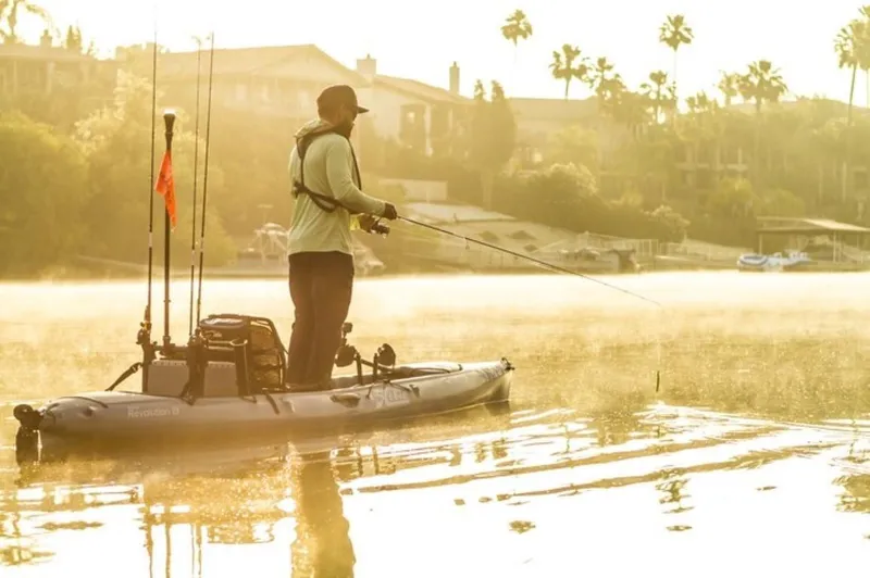 Slide: The Image of Man fishing on a 2023 Hobie Revolution 13 kayak in a serene lake at sunrise. - 9
