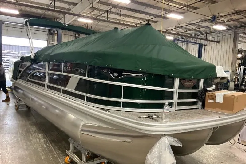The Image of 2026 Bennington 24 M L-Bench pontoon boat with green cover in a warehouse. - 0