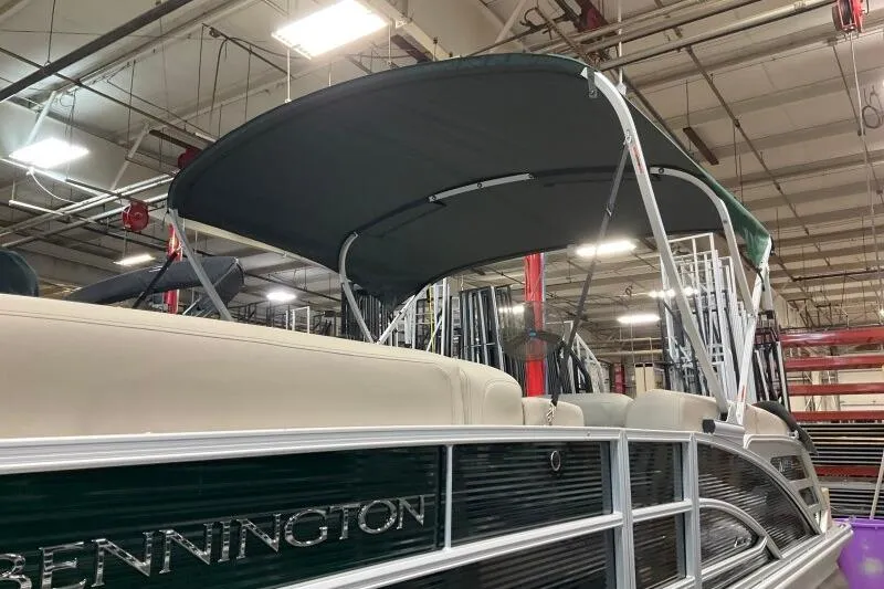Slide: The Image of 2026 Bennington 24 M L-Bench pontoon boat with canopy in a showroom. - 10