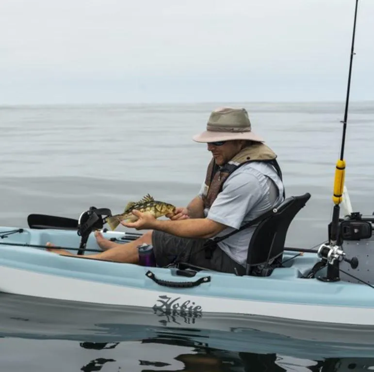 Slide: The Image of Man fishing on a 2023 Hobie Passport 12.0 kayak, holding a fish. - 2
