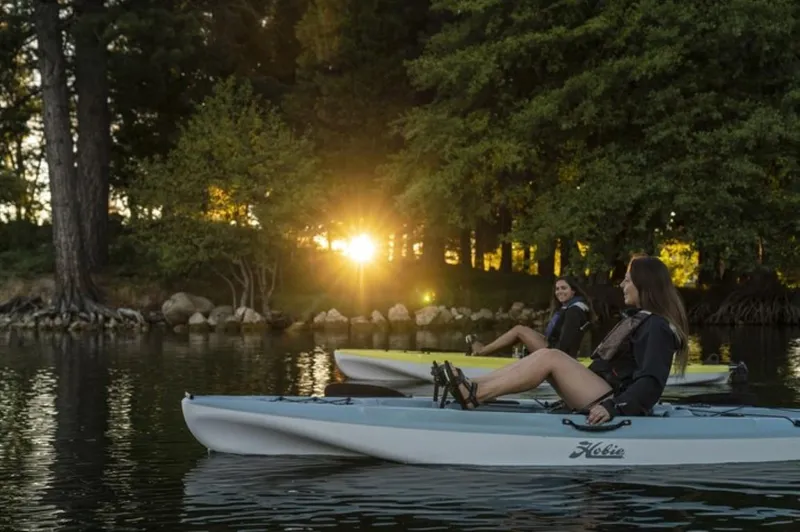 Slide: The Image of Two women kayaking on a lake at sunset in 2023 Hobie Passport 12.0 kayaks. - 3