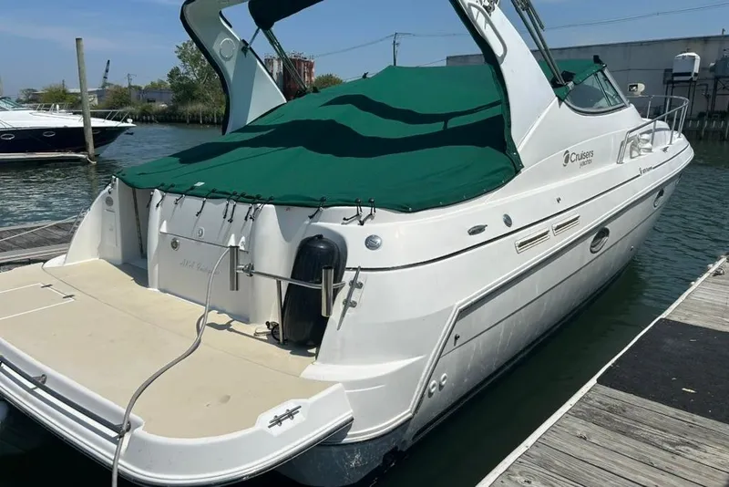 The Image of 2000 Cruisers Yachts 3575 Express docked, featuring green cover and spacious deck. - 1