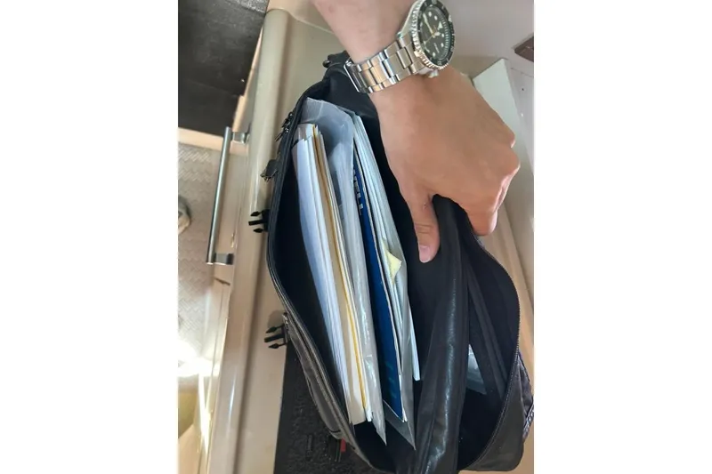 Slide: The Image of Hand holding a black bag filled with documents on a 2000 Cruisers Yachts 3575 Express. - 18