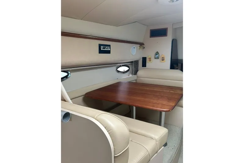Slide: The Image of Interior of 2000 Cruisers Yachts 3575 Express with wooden table and beige seating. - 11