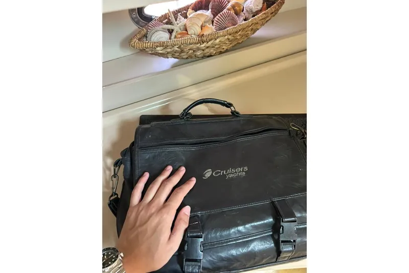 Slide: The Image of Hand touching a Cruisers Yachts bag beside a basket of seashells. - 17