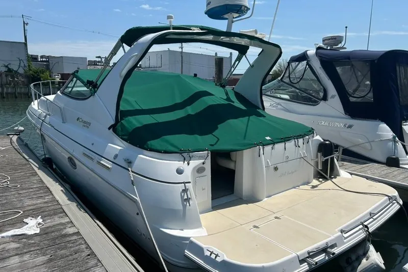 The Image of 2000 Cruisers Yachts 3575 Express docked with green cover, side view. - 3