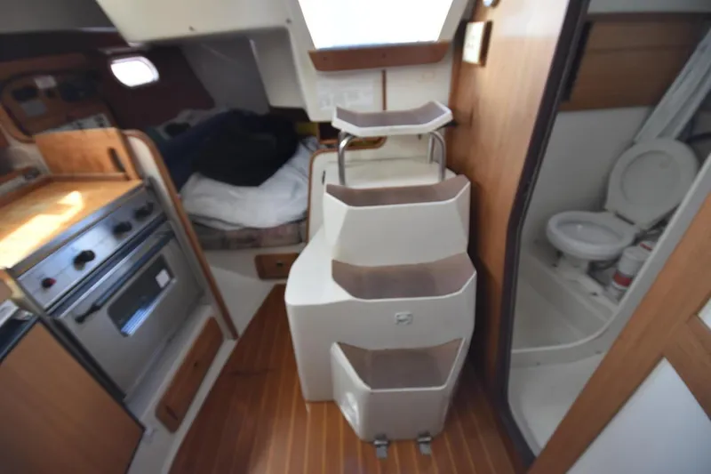 Slide: The Image of Interior of a 2001 Catalina 310 sailboat featuring a compact kitchen and bathroom. - 48