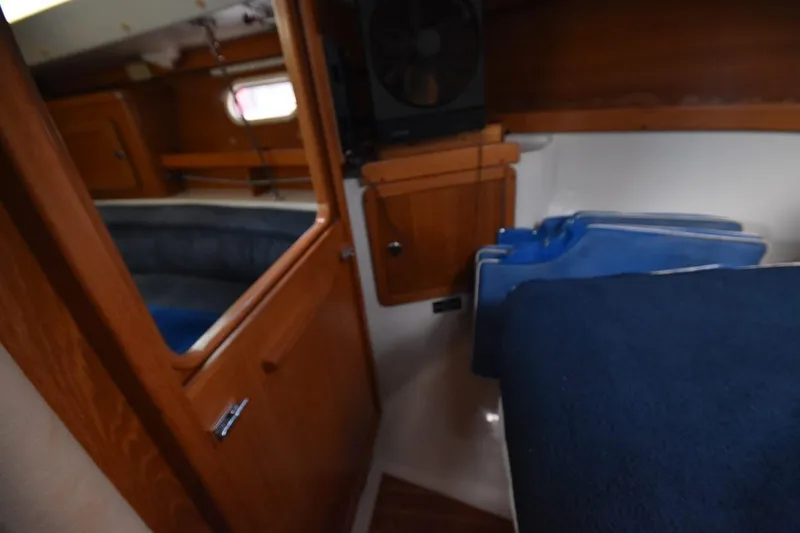 Slide: The Image of Interior of a 2001 Catalina 310 sailboat, featuring wooden cabinetry and blue cushions. - 52