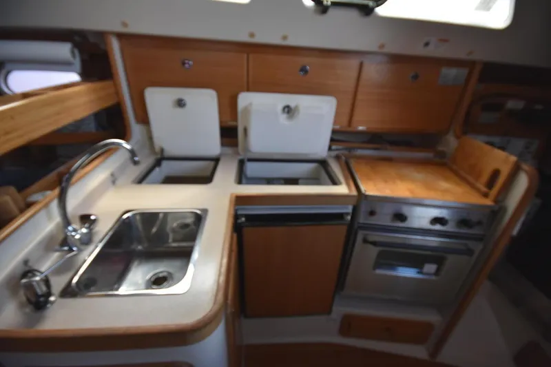Slide: The Image of 2001 Catalina 310 yacht kitchen with sink, stove, and wooden cabinetry. - 57